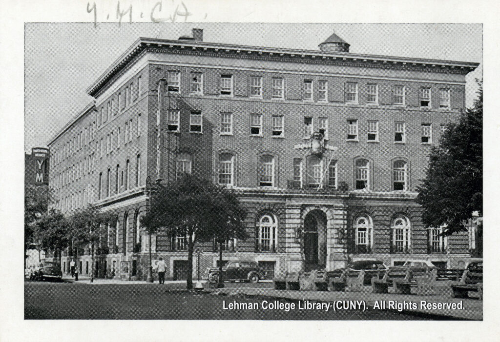 Image of the Bronx Union YMCA Building with several trees, cars, and benches. An unknown person appears to have just crossed a street.