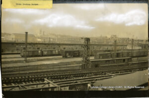Image of box cars, factories, and the Macombs Dam Bridge in the background.