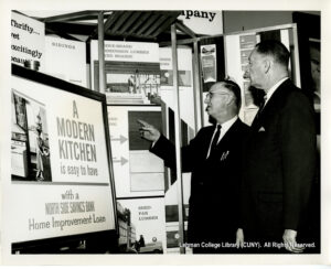 Image of two men in dark suits looking at posters advertising modern kitchens, lumber boards, sidings, and more, all "easy to have with a Norht Side Savings Bank Home Improvement Loan"