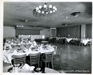 Image of a dance floor and tables with desserts, silverware, water, and numbers on them -- seemingly set up for a wedding.