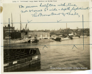 Image of factory buildings, boats, and rail bridges over a river.