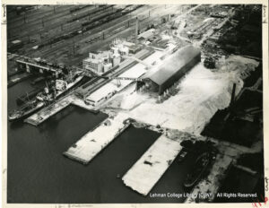 Aerial Image of a pier next to a railroad yard. Gypsum appears to be piled everywhere and a sign says "National Gypsum Co."