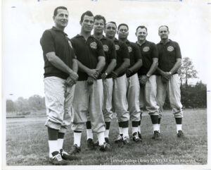 Several men wearing polo shirts, sweat pants, and cleats looking at the camera.