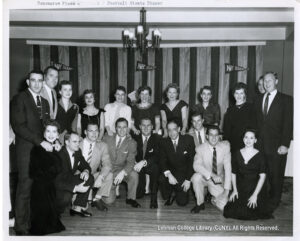 Image of about a dozen men in suits and women in dresses smiling at the camera. Pennants saying NY Giants are visible.