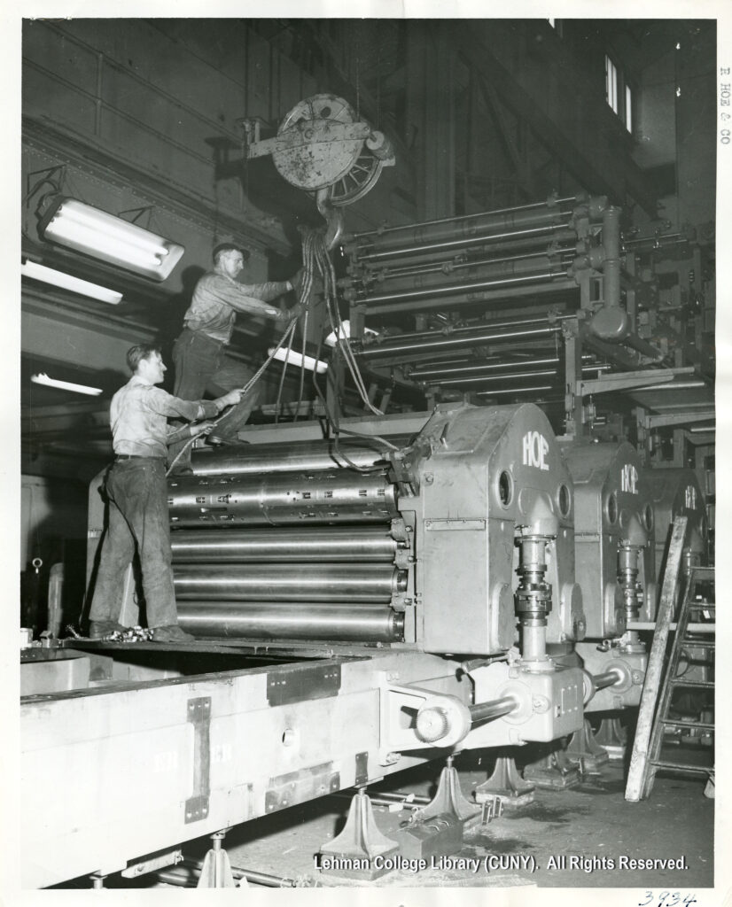 Image of two workers holding cables on printing press equipment