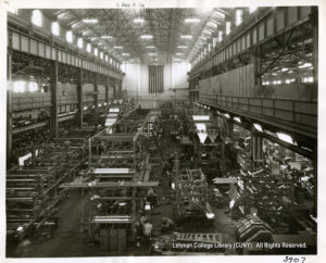 Image of a large, high ceilinged room, with printing presses and workers in motion throughout.