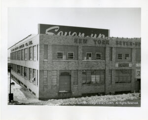 Image of a factory building with a sign saying "New York Seven-Up." Several windows are open.