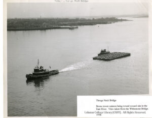 Image of a tug boat towing a caisson on a large river.