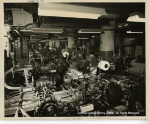 Image of a factor with lots of machines and some people working on those machines.