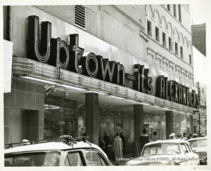 Image of a store that says "Uptown its Alexanders" and has cars and people outside.