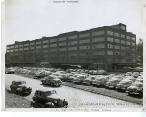 Image of a large building surrounded with dozens of parked cars
