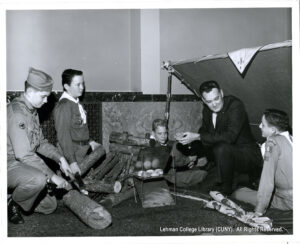Several men and boys are seated around a shelter and firewood inside a bank branch