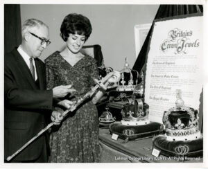 Image of a man and a woman holding a jeweled staff and looking at jeweled crowns