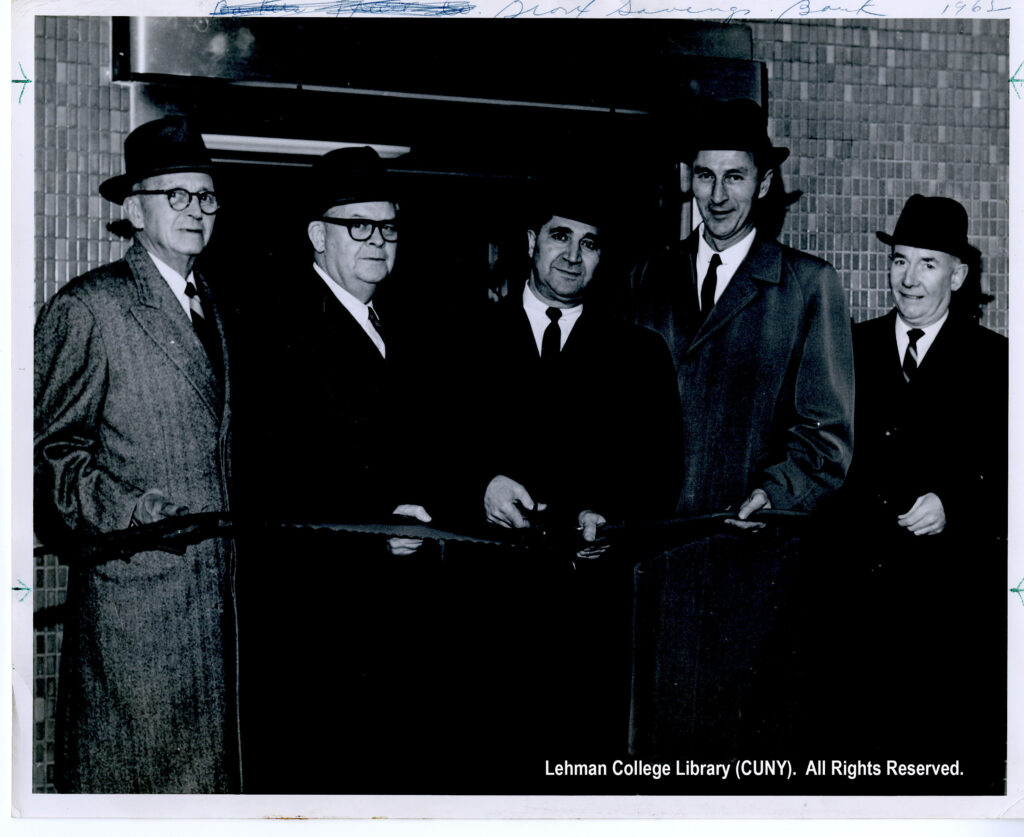 Image of several older men wearing dark-colored suits cutting a ribbon to open a drive in for the Bronx Savings Bank