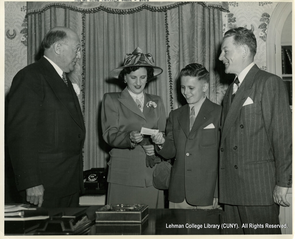 Image of a boy in a blazer showing tickets to a woman in a suit and hat. Two men in suits look on