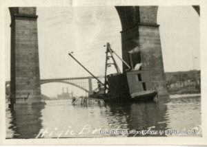 Image of a barge being sunk. Washington Bridge and smoke stacks are visible.